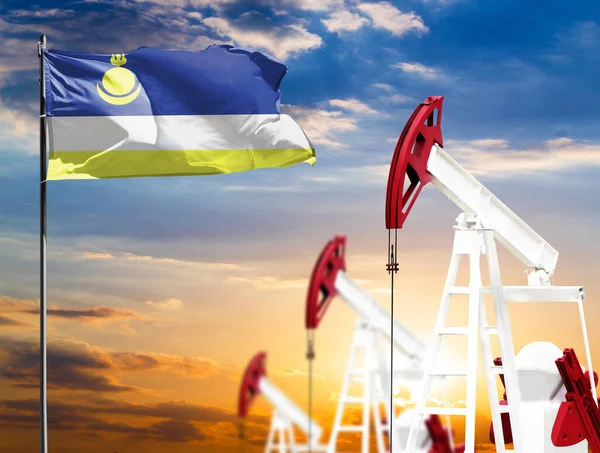 Oil rigs against the backdrop of the colorful sky and a flagpole with the flag of Buryatia. The concept of oil production, minerals, development of new deposits.