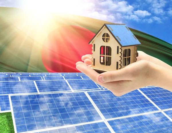 The photo with solar panels and a woman\'s palm holding a toy house shows the flag of Bangladesh in the sun.