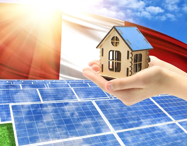 The photo with solar panels and a woman\'s palm holding a toy house shows the flag of Peru in the sun.