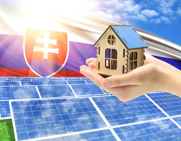 The photo with solar panels and a woman\'s palm holding a toy house shows the flag of Slovakia in the sun.