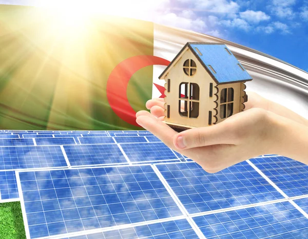 The photo with solar panels and a woman\'s palm holding a toy house shows the flag of Algeria in the sun.