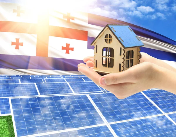 The photo with solar panels and a woman\'s palm holding a toy house shows the flag of Adjara in the sun.
