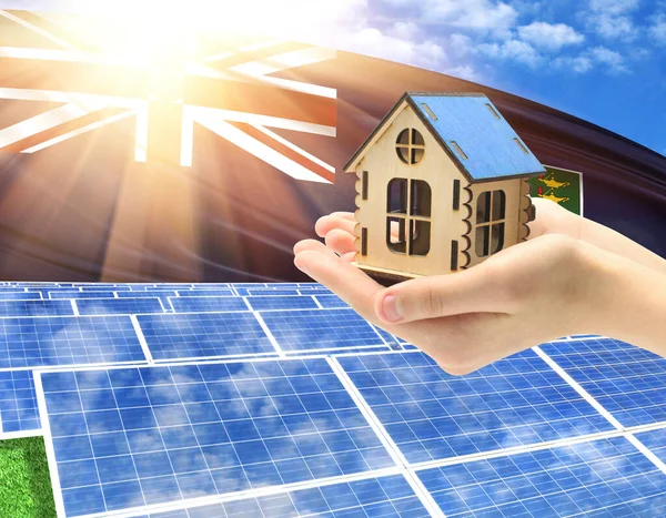 The photo with solar panels and a woman\'s palm holding a toy house shows the flag of British Virgin Islands in the sun.