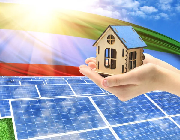 The photo with solar panels and a woman\'s palm holding a toy house shows the flag of Dagestan in the sun.