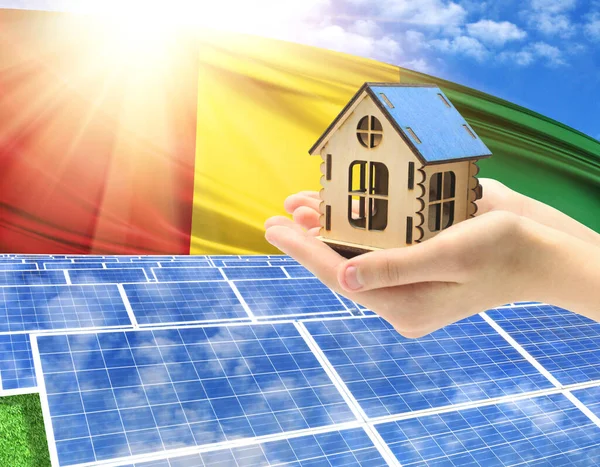 The photo with solar panels and a woman\'s palm holding a toy house shows the flag of Benin in the sun.