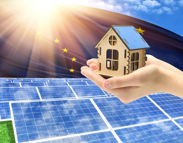 The photo with solar panels and a woman\'s palm holding a toy house shows the flag State of Alaska in the sun.