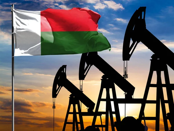 Oil rigs against the backdrop of the colorful sky and a flagpole with the flag of Madagascar. The concept of oil production, minerals, development of new deposits.