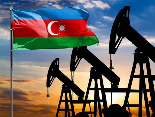 Oil rigs against the backdrop of the colorful sky and a flagpole with the flag of Azerbaijan. The concept of oil production, minerals, development of new deposits.