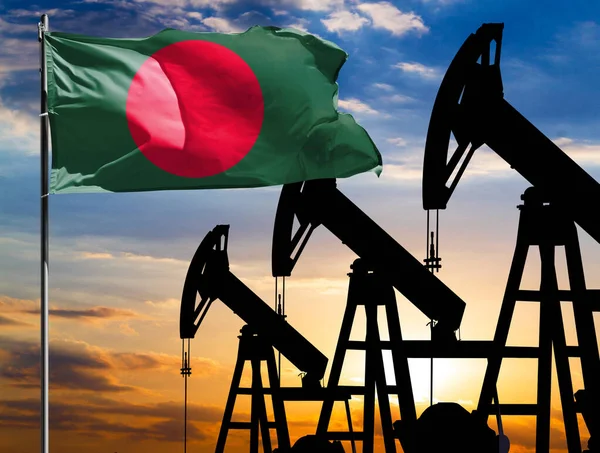 Oil rigs against the backdrop of the colorful sky and a flagpole with the flag of Bangladesh. The concept of oil production, minerals, development of new deposits.