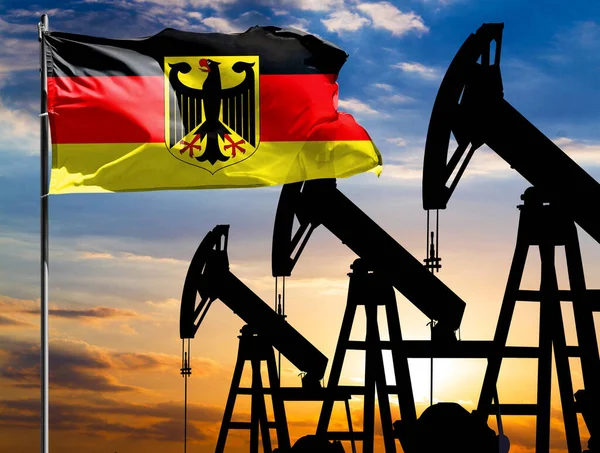 Oil rigs against the backdrop of the colorful sky and a flagpole with the flag of Germany. The concept of oil production, minerals, development of new deposits.