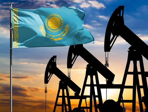 Oil rigs against the backdrop of the colorful sky and a flagpole with the flag of Kazakhstan. The concept of oil production, minerals, development of new deposits.