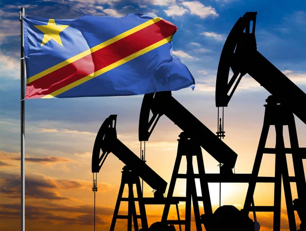 Oil rigs against the backdrop of the colorful sky and a flagpole with the flag of Congo Democratic. The concept of oil production, minerals, development of new deposits.