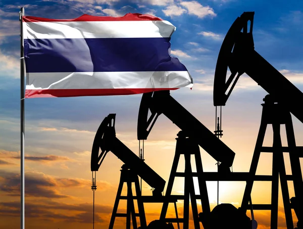Oil rigs against the backdrop of the colorful sky and a flagpole with the flag of Thailand. The concept of oil production, minerals, development of new deposits.