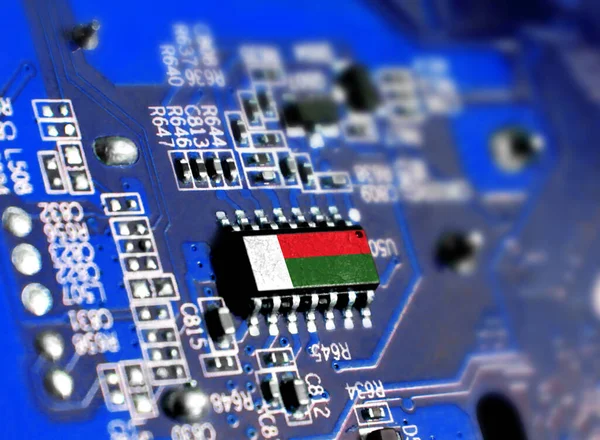 Electronic board with embedded microchip and shown flag of Madagascar. The concept of modern computer technologies.