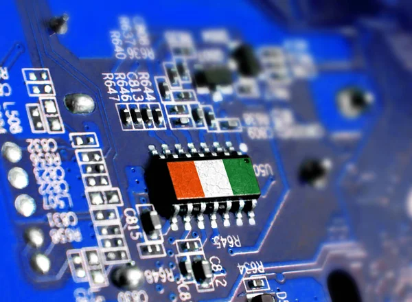 Electronic board with embedded microchip and shown flag of Cote d,lvoire. The concept of modern computer technologies.