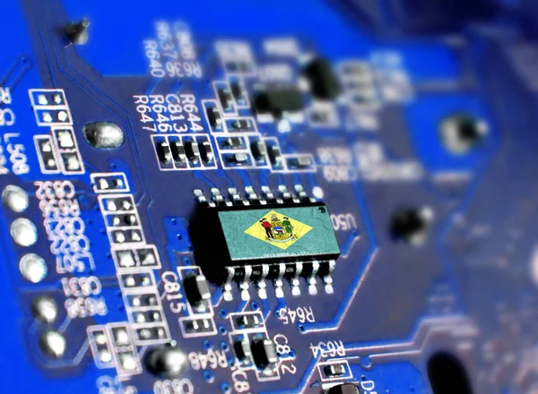 Electronic board with embedded microchip and shown flag State of Delaware. The concept of modern computer technologies.