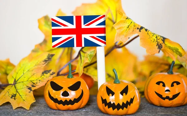 Colorful Halloween background with smiley pumpkins and toy flag of United Kingdom