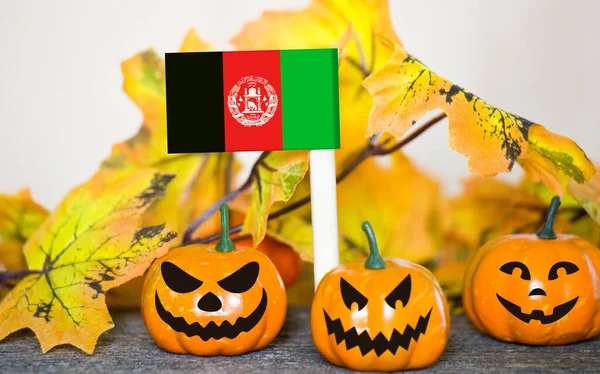 Colorful Halloween background with smiley pumpkins and toy flag of Afghanistan
