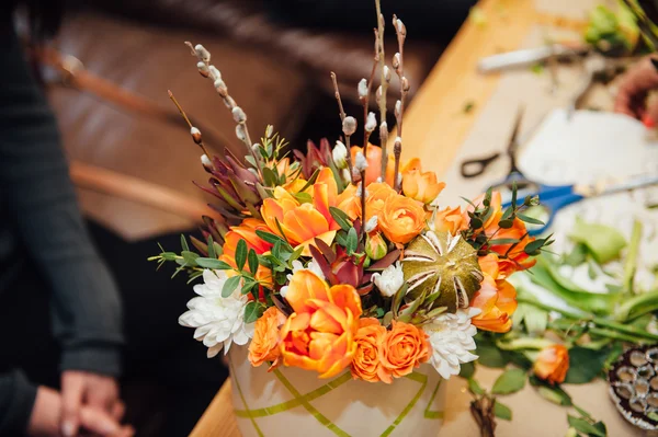 Bloemist maakt een mand met verschillende bloemen — Stockfoto