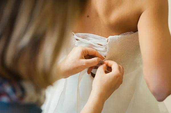 Družičky pomáhají nosit svatební šaty — Stock fotografie