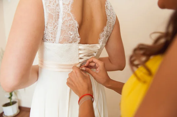 Bruidsmeisjes helpen te dragen van een trouwjurk — Stockfoto