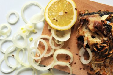 Bir ahşap tahta üzerinde limon dilimleri ile ızgara sazan