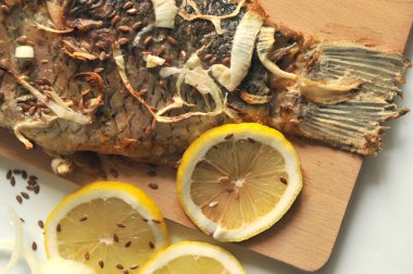 Bir ahşap tahta üzerinde limon dilimleri ile ızgara sazan