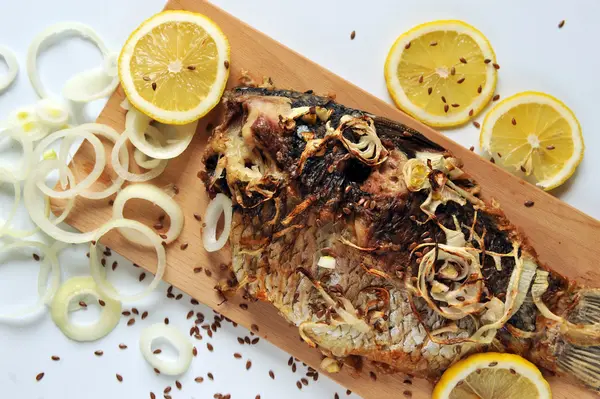 Grilled carp with lemon slices on a wooden board — Stock Photo, Image