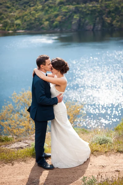 Bride and groom walking at the river — Stock Photo, Image