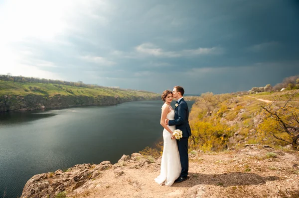 Bruid en bruidegom lopen aan de rivier — Stockfoto