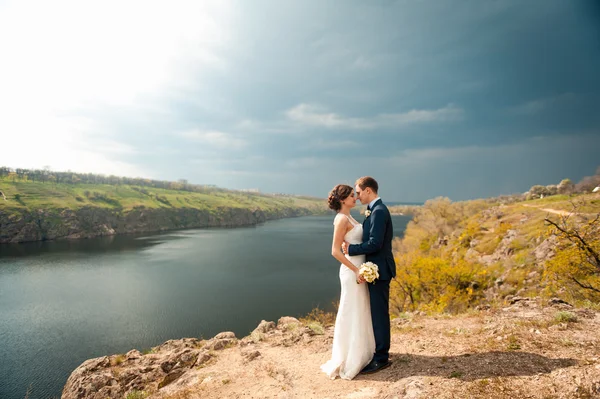 Bride and groom walking at the river — Stock Photo, Image
