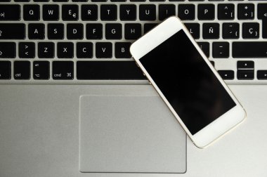 Açık laptop ve beyaz masa üstünde smartphone