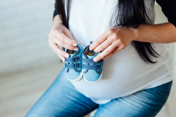 Kleine Schuhe für Baby im Bauch einer Schwangeren — Stockfoto