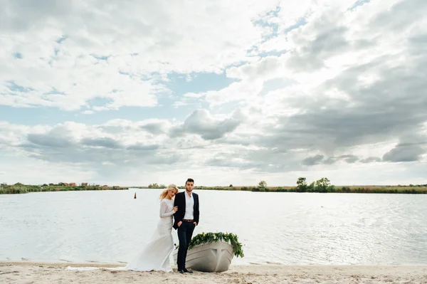 Наречений і наречений ходять біля човна на річці — стокове фото