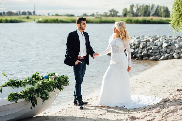 Наречений і наречений ходять біля човна на річці — стокове фото