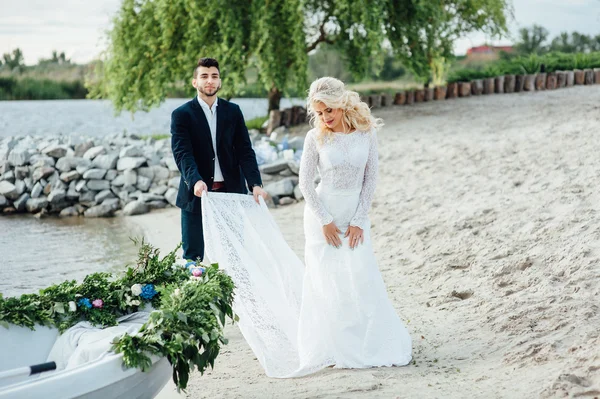 Nevěsta a ženich, kousek od lodi na řece — Stock fotografie