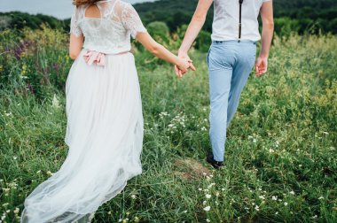 Mutlu gelin ve damat yeşil çimenlerin üzerinde yürüyüş