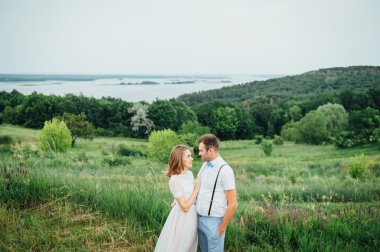 Mutlu gelin ve damat yeşil çimenlerin üzerinde yürüyüş