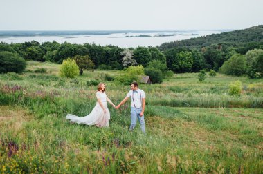 Mutlu gelin ve damat yeşil çimenlerin üzerinde yürüyüş