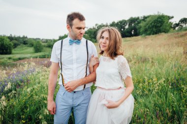 Mutlu gelin ve damat yeşil çimenlerin üzerinde yürüyüş