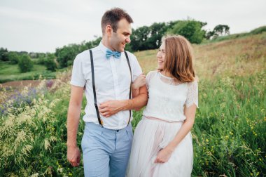 Mutlu gelin ve damat yeşil çimenlerin üzerinde yürüyüş