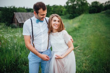 Mutlu gelin ve damat yeşil çimenlerin üzerinde yürüyüş
