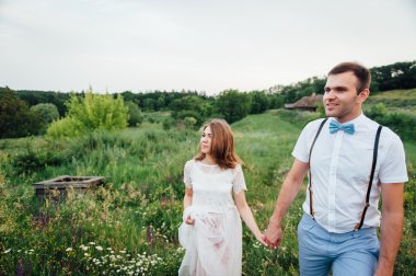 Mutlu gelin ve damat yeşil çimenlerin üzerinde yürüyüş