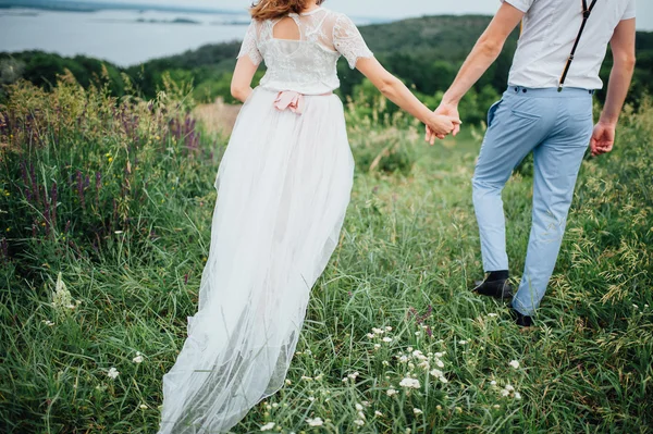 Boldog menyasszony és a vőlegény a zöld fűben járás — Stock Fotó