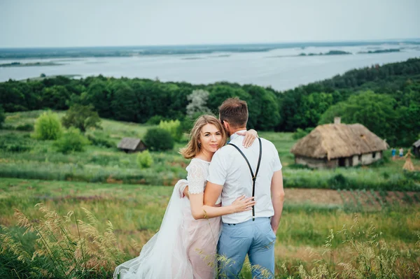 Gelukkige bruid en bruidegom lopen op het groene gras — Stockfoto