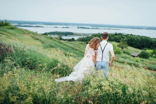 Mutlu gelin ve damat yeşil çimenlerin üzerinde yürüyüş — Stok fotoğraf