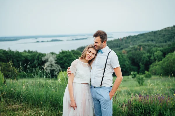 Lyckliga bruden och brudgummen gå på det gröna gräset — Stockfoto