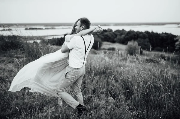 Lyckliga bruden och brudgummen gå på det gröna gräset — Stockfoto