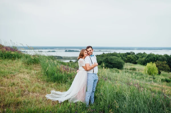 Gelukkige bruid en bruidegom lopen op het groene gras — Stockfoto