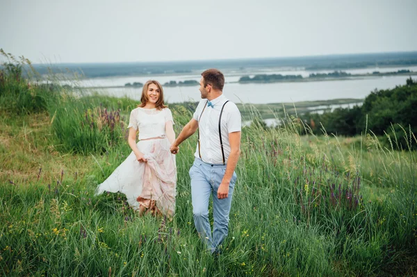 Noiva feliz e noivo andando na grama verde — Fotografia de Stock